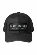 A black trucker hat with a black mesh back and a front patch reading 'HANDS RAISED' and 'WORK, GRIT, EARNED.' on a plain white background.