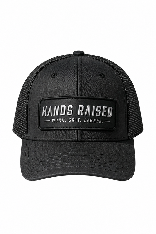 A black trucker hat with a black mesh back and a front patch reading 'HANDS RAISED' and 'WORK, GRIT, EARNED.' on a plain white background.